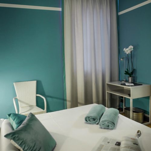 camera di albergo realizzata in bianco e verde acqua con carta da parati e tessuti sartoriali su misura abbinati