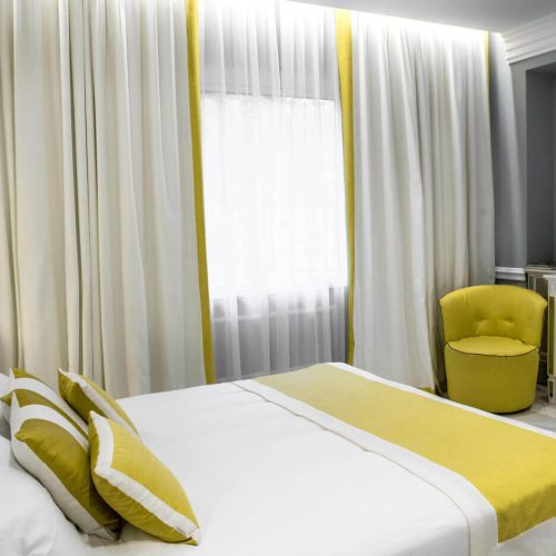 camera di albergo 4 stelle gialla e bianca accogliente e moderna con rivestimenti ignifughi a norma di legge
